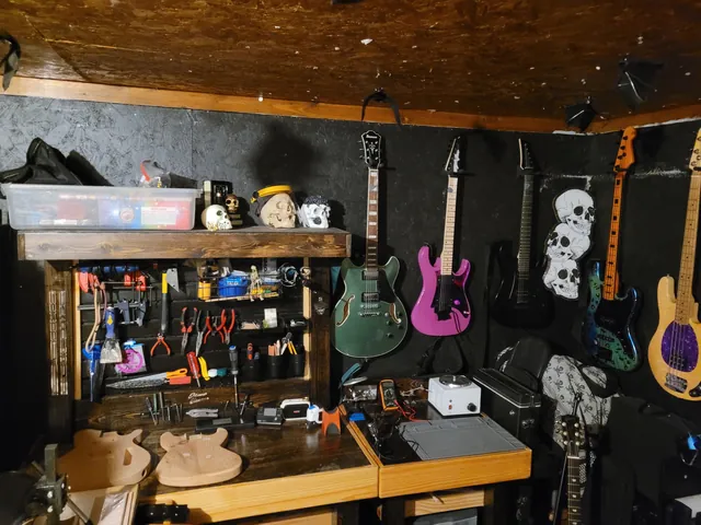 The shop: workbenches, a pegboard of tools, guitars on the wall and skulls on a shelf.