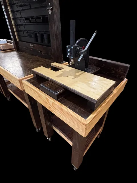 A workbench with a press mounted on the right side, photographed against a black background.