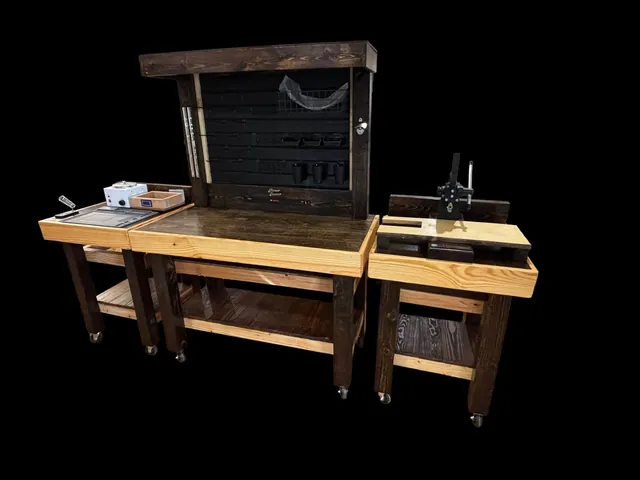 The full row of workbenches with the tool wall behind, photographed against a black background.